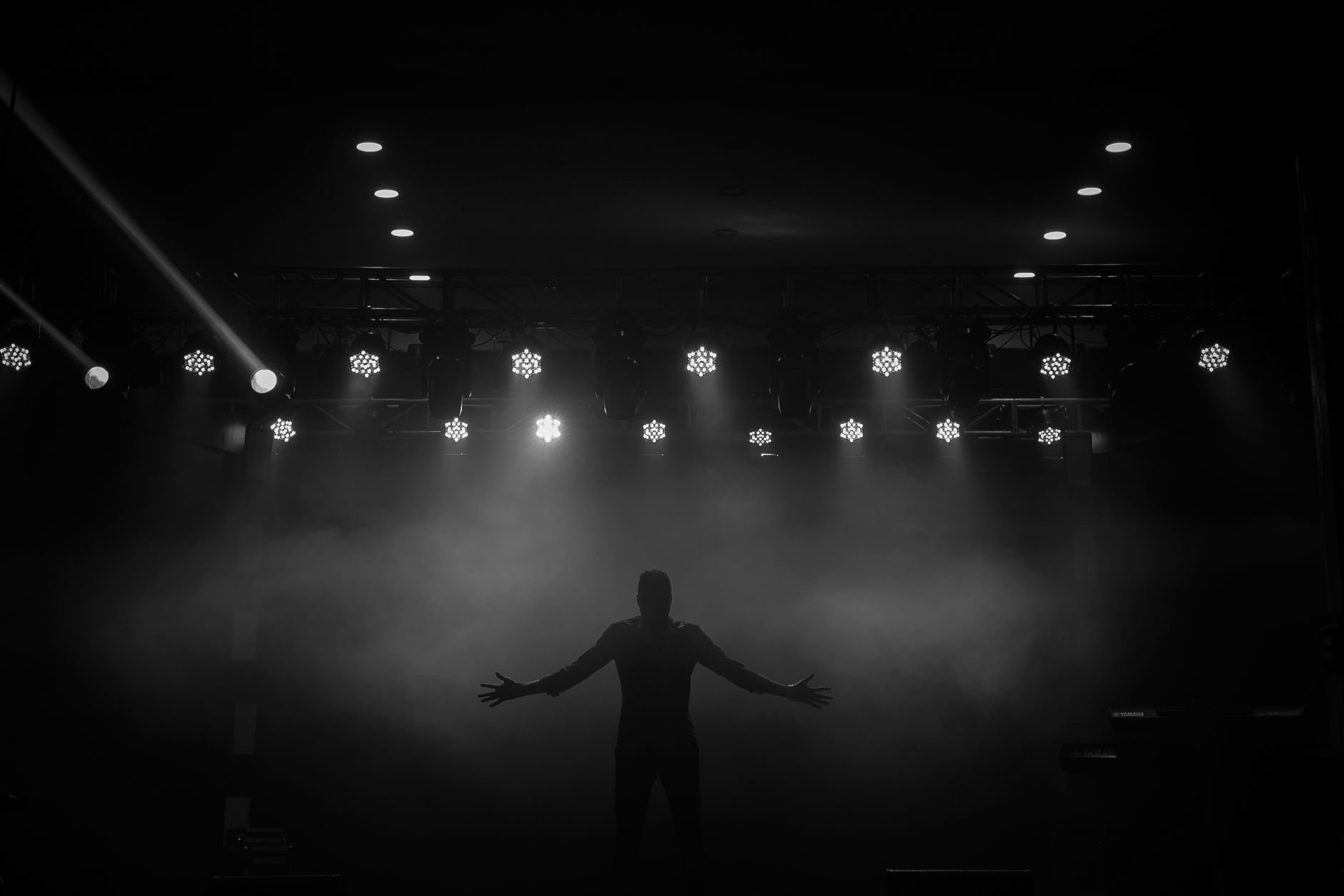 Dramatic silhouette of a performer on stage with bright lights and fog